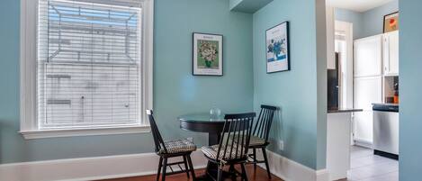 A dining area with a round table, four chairs, and two framed botanical prints on the wall.