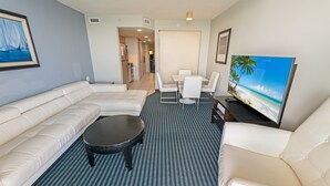 Una sala de estar moderna con un sofá, una mesa de centro, un televisor y un comedor con sillas y una mesa.
