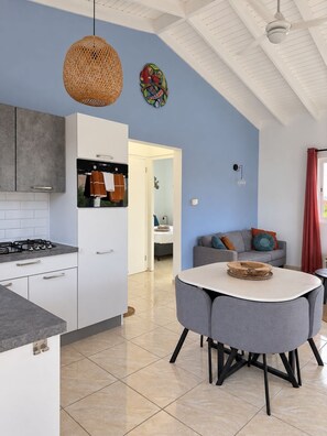 A modern kitchen with a gas stove, white cabinets, and a dining area with a round table and grey chairs. - Quietly located vacation villa with a private pool (Fontein)