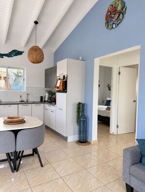 A modern kitchen with white cabinets, a dining table with chairs, a hanging light fixture, and a blue wall. - Quietly located vacation villa with a private pool (Fontein)