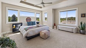 A bedroom with a bed, a ceiling fan, large windows, and a view of the outdoors. - Beautiful end unit home with big horizon views! (Bend)