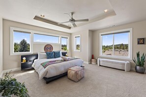 A bedroom with a bed, a ceiling fan, large windows, and a view of the outdoors. - Beautiful end unit home with big horizon views! (Bend)