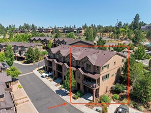 A residential area with multiple two-story houses, a clear sky, and a road with vehicles. - Beautiful end unit home with big horizon views! (Bend)