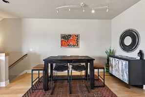A dining area with a table, chairs, a painting, a mirror, and a cabinet. - Beautiful end unit home with big horizon views! (Bend)