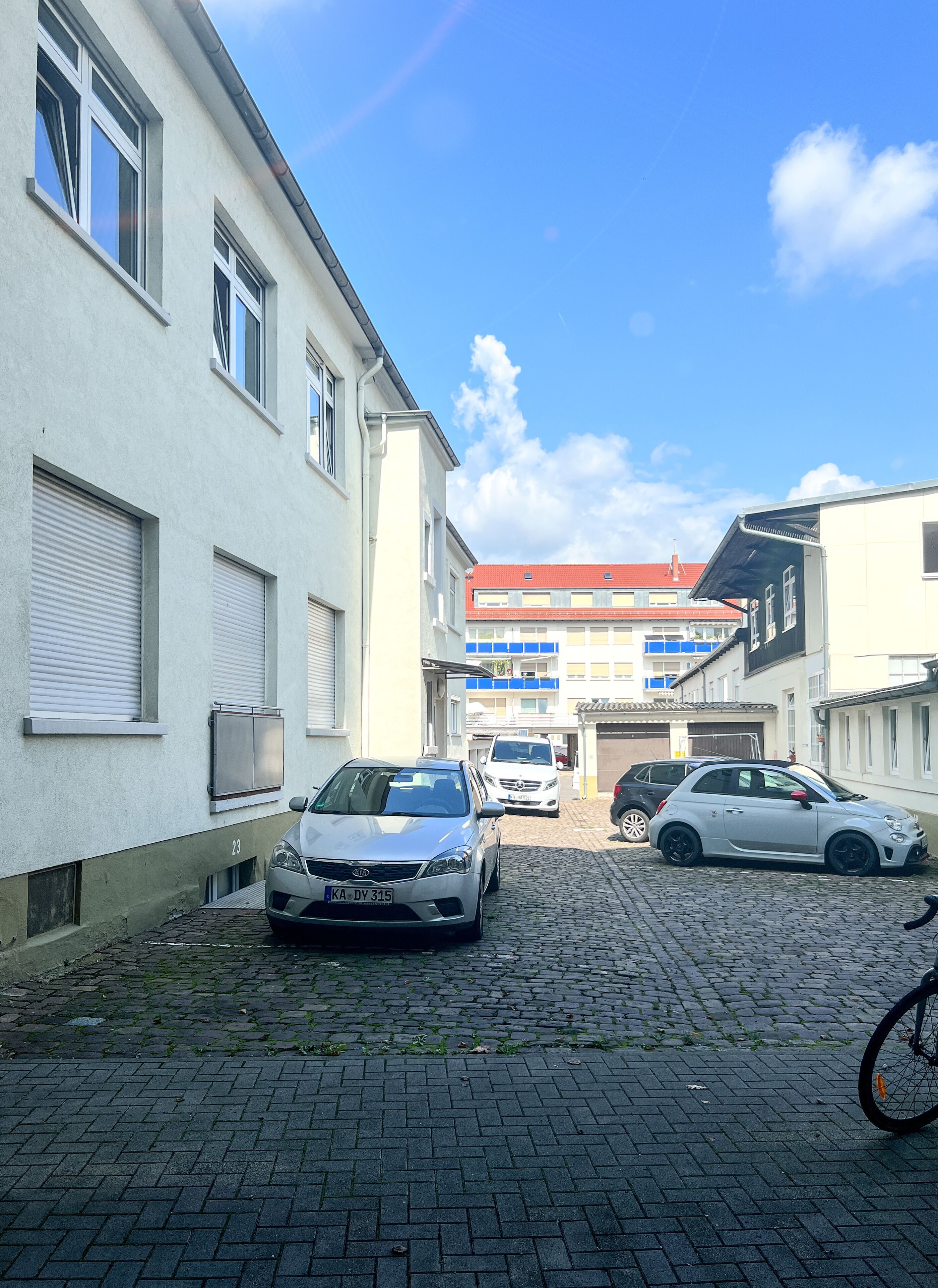 Una calle adoquinada con coches aparcados y edificios.