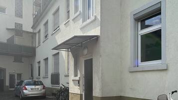 Een gebouw met een terras van bakstenen, een auto ervoor en een fiets tegen de muur geleund.