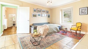 Ein Schlafzimmer mit einem Bett, einem Sessel, einem Teppich, einem Nachttisch und einem Fenster.
