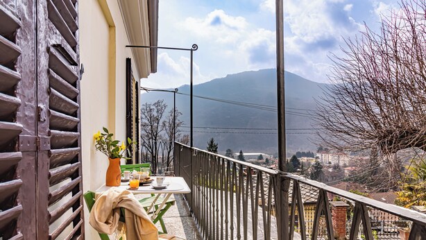Ein Balkon mit Tisch, Stühlen, einem Blumentopf und Blick auf einen Berg.