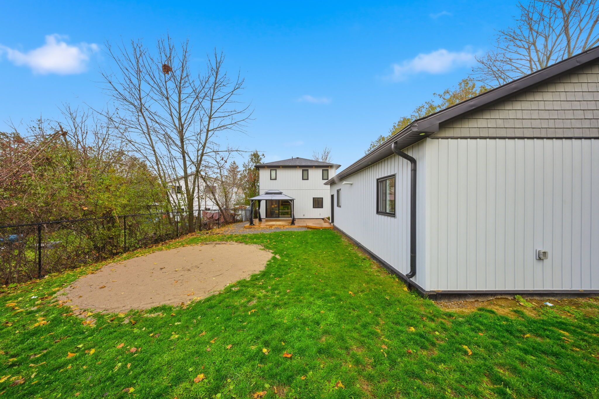 Ein Wohnhaus mit gepflegtem Rasen, einer separaten Garage und einem zweistöckigen Haus im Hintergrund.