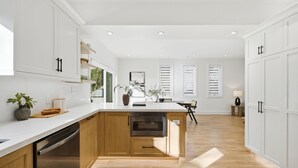 A modern kitchen with white cabinetry, a wooden island, and built-in appliances. - Lake Simcoe Ice Fishing Basecamp • Sleeps 10–12 • Heated Shop (Beaverton)