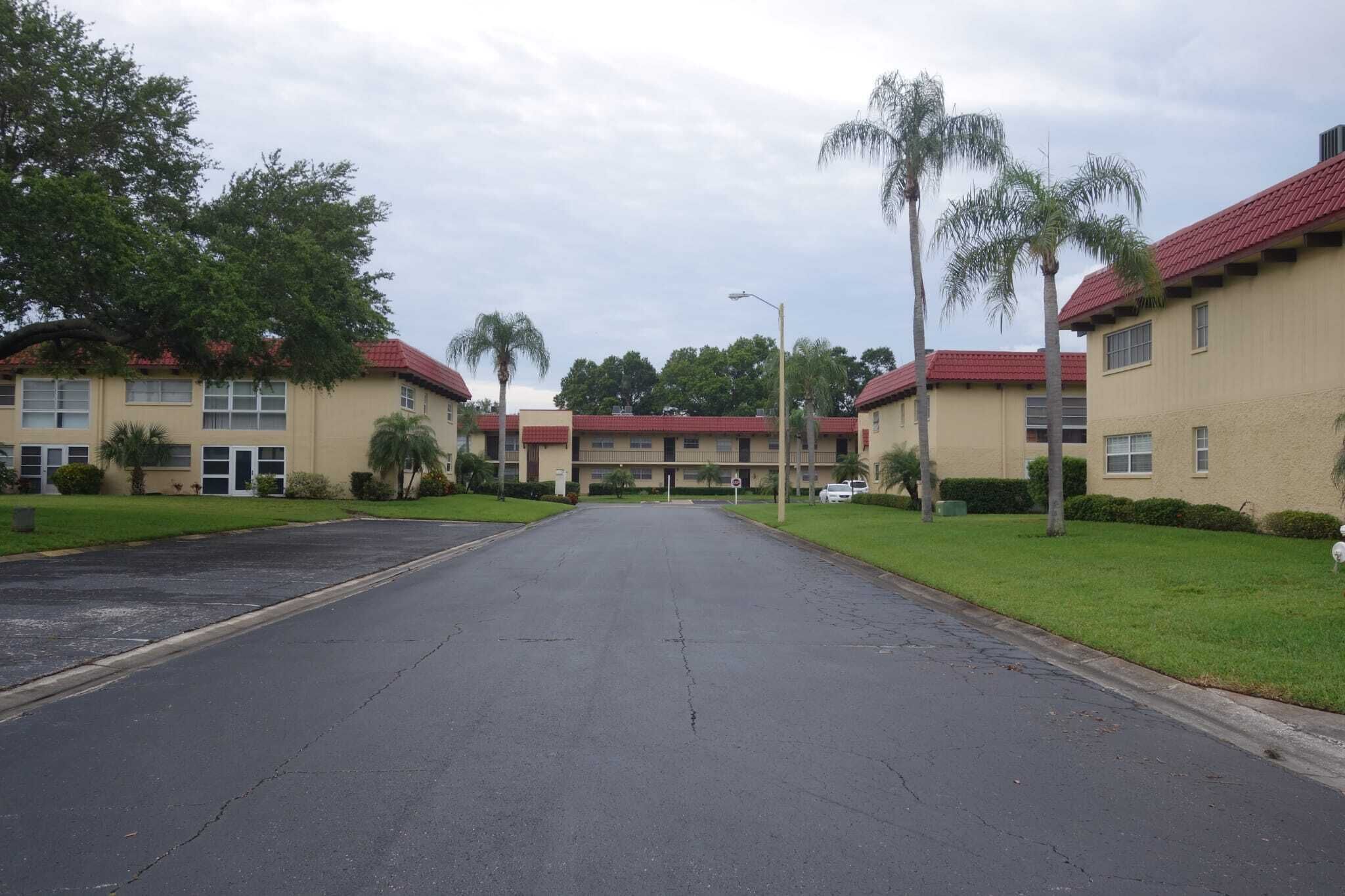 A building with multiple red-roofed units, a central entrance, and surrounding greenery.