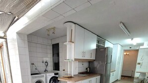 Una cucina moderna con mobili bianchi, lavatrice integrata e un piano di lavoro in legno.