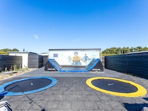 En trampolinpark med to trampoliner og et stort muralmaleri.