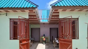 A courtyard with two open-sided structures, a central table, and a chair. - Magogoni Guest House (Mafia Island)