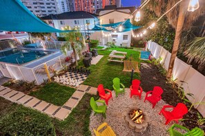 Un jardin avec une piscine, un espace salon extérieur et un foyer.