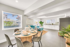 A modern kitchen with white cabinets, a stainless steel refrigerator, and a window overlooking the city.