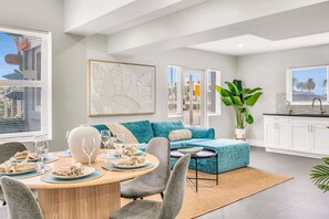 A modern living room with a dining area, a sofa, and a kitchen.