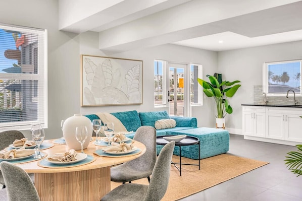 A modern living room with a dining area, a sofa, and a kitchen.