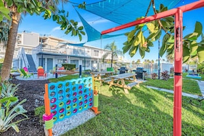 A patio area with a children's play area, including a tire hop game, picnic tables, and outdoor seating.