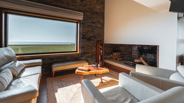 Ein modernes Wohnzimmer mit großem Fenster, Kamin und Steinwand.