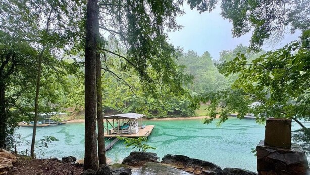 A serene lakeside view with a dock and a covered seating area. - Scenic 4‑BR sleeps 14 with Lake View, Decks, Private Dock, Kayaks, Canoe (LaFollette)