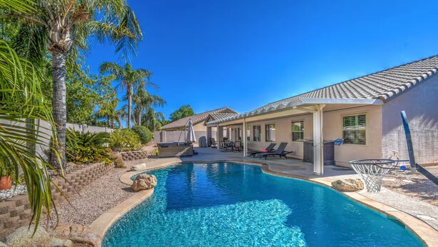 Une piscine avec des chaises longues et un espace patio couvert.