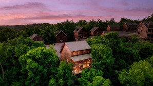 A lodge with multiple wooden cabins surrounded by dense forest, featuring a prominent central building with a balcony. - Free Dollywood Tix•Heated Pool•GameRoom•Modern (Sevier)