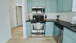 Een moderne keuken met blauwgroene kastjes, roestvrijstalen apparatuur en een houten vloer.