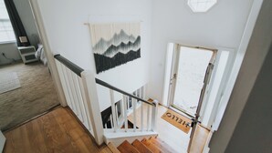 Een trap met een houten leuning en een witte deur met een deurmat waarop 'WELCOME' staat.