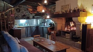 Ein gemütliches Wohnzimmer mit Kamin, einem Esstisch und einer Küchenzeile mit modernen Geräten.
