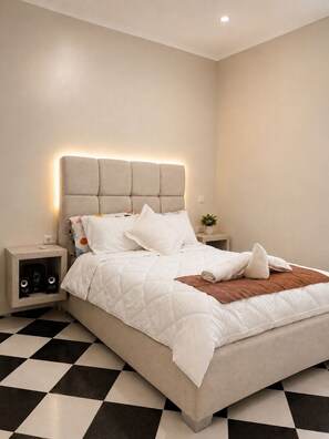 Ein modernes Schlafzimmer mit einem Bett, einem Nachttisch mit Lautsprechern und einem Schachbrettboden.