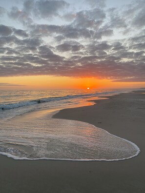 A beach with a curved shoreline and waves gently lapping at the sand. - Gulf front complex West Beach. Steps to the sand! Sleeps 6. Sunrise Village 102 (Gulf Shores)