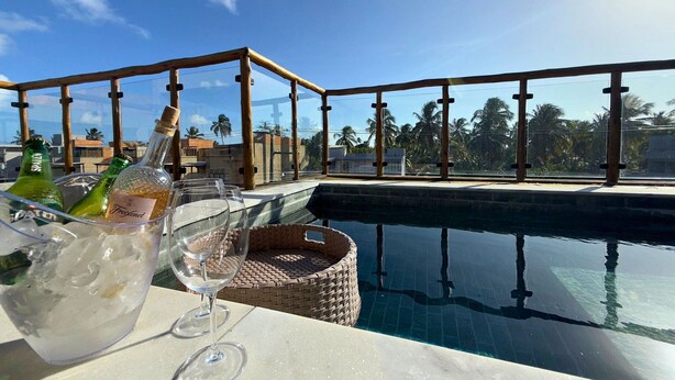 Ein Poolbereich mit freiem Blick auf den Pool, ein Korbstuhl und ein Tisch mit Flaschen und Gläsern.