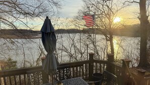 Une terrasse avec une table et des chaises, donnant sur une étendue d’eau, avec un drapeau américain.