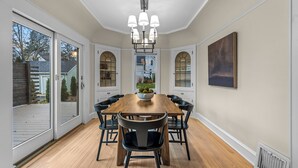 A dining room with a wooden table, black chairs, and a chandelier.
