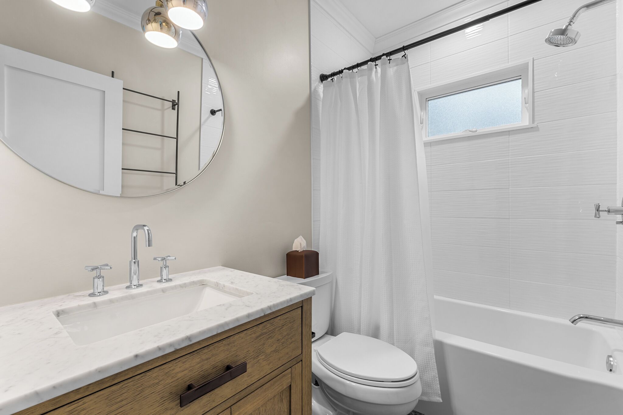 Un bagno con lavandino, specchio e water bianchi, e una doccia con tenda.