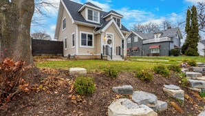 A two-story house with a front porch, a stone pathway, and a well-maintained lawn.