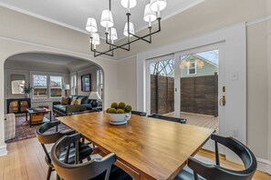 A spacious dining area with a wooden table and modern chairs, a chandelier, and a view of the backyard through large sliding glass doors. - Remodeled Luxury 3BR - Walk to Cedarburg Downtown (Cedarburg)