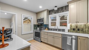 A modern kitchen with beige cabinetry, stainless steel appliances, and a white countertop.