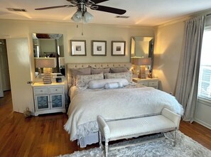 A bedroom with a large bed, two bedside tables, a ceiling fan, and a window with curtains. - 3-bedroom Cottage new LSU! (Baton Rouge)