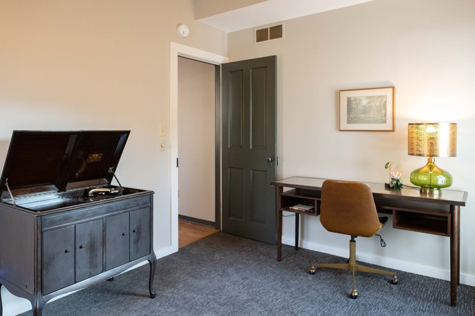 A compact room with a desk, chair, and a music player on a cabinet.