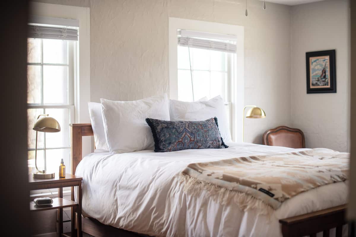 Une chambre à coucher avec un lit, des lampes de chevet, une table de chevet et une fenêtre avec des stores.