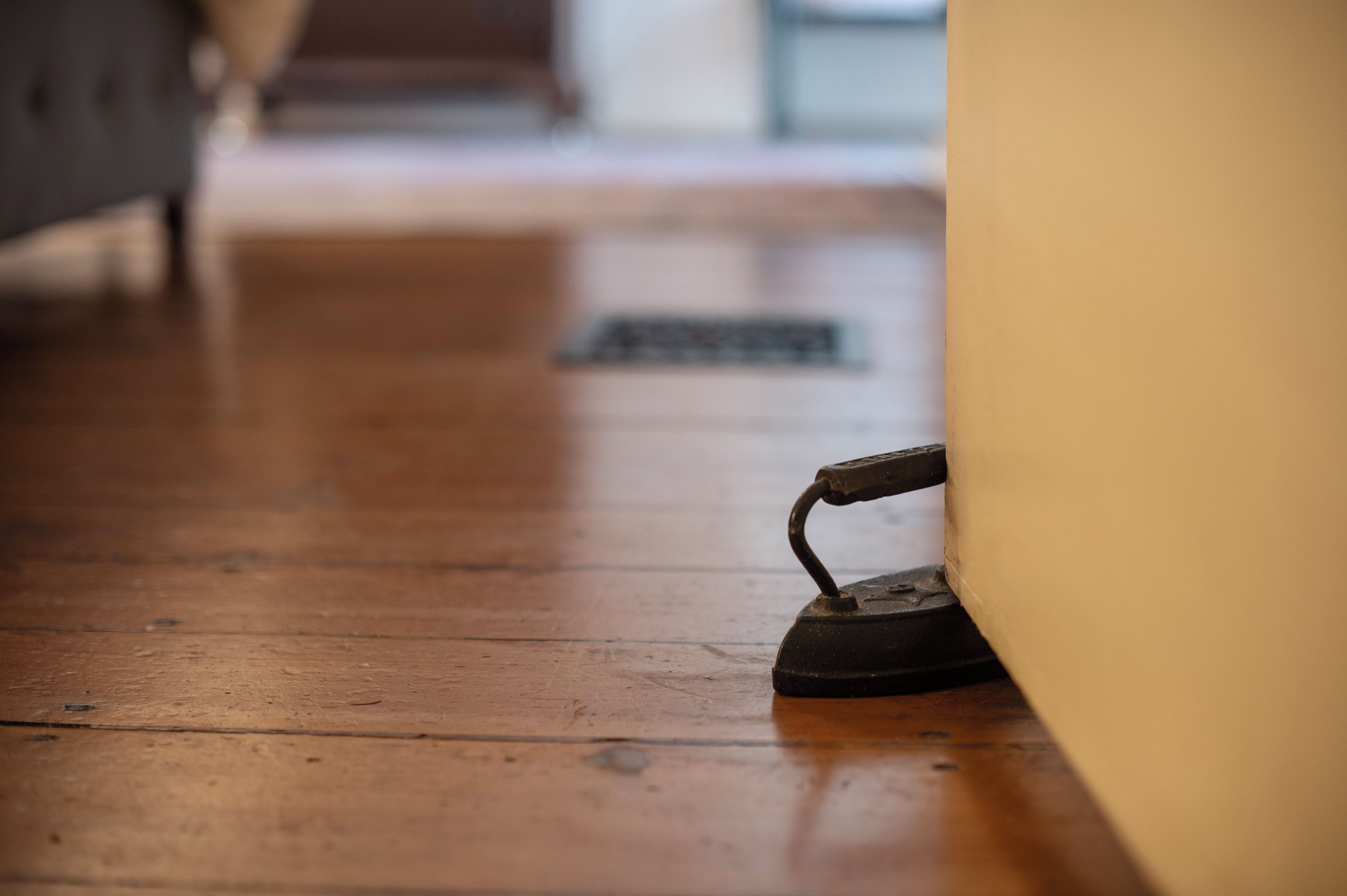 A wooden floor with a metal object, possibly a tool, near a wall.