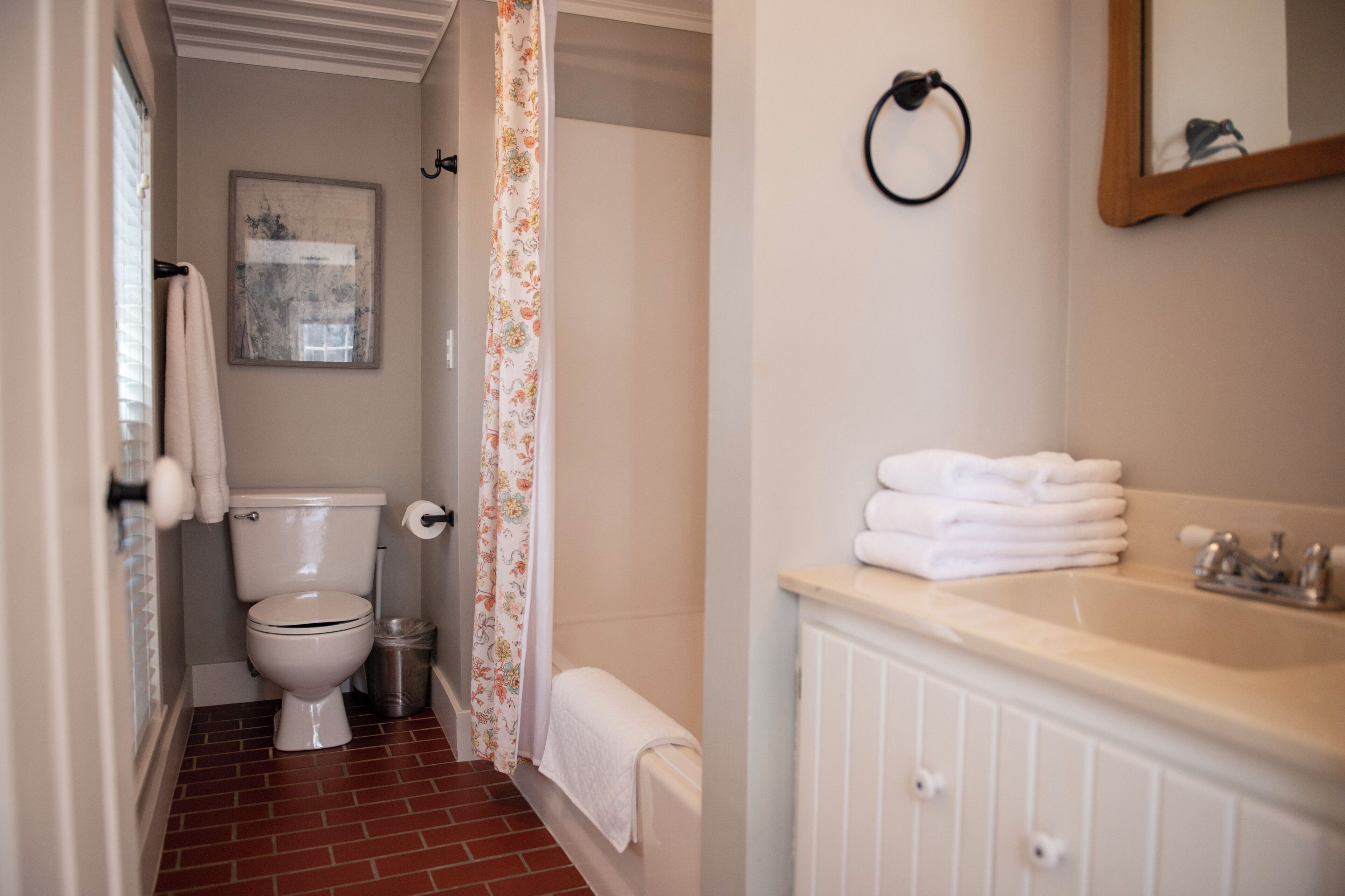 A bathroom with a toilet, a shower curtain, a sink, and a towel rack.