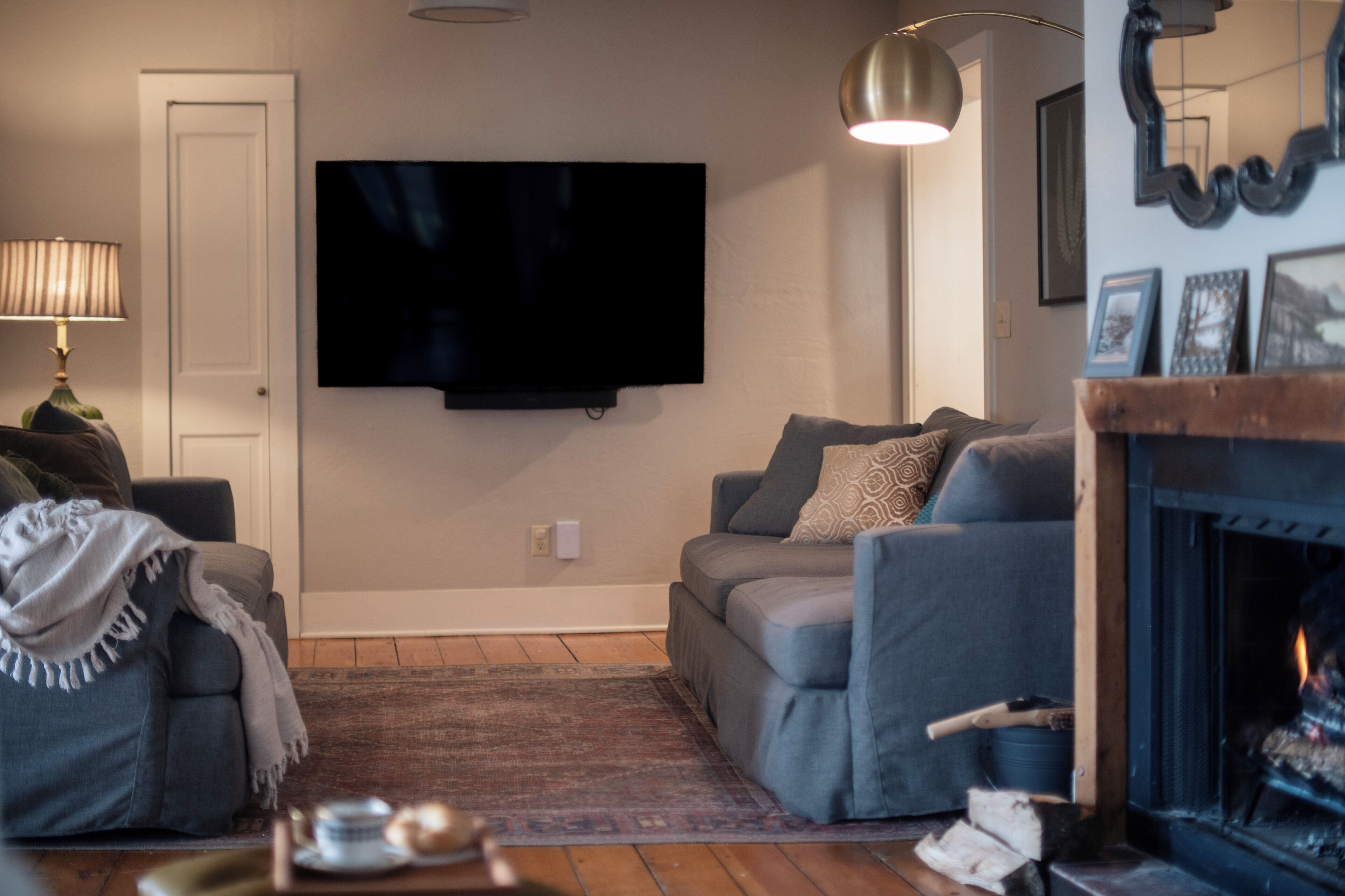 Ein Wohnzimmer mit Flachbildfernseher, einer Couch, einem Kamin und einer Lampe.