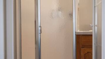 Une salle de bain avec une douche, des toilettes et un meuble en bois.