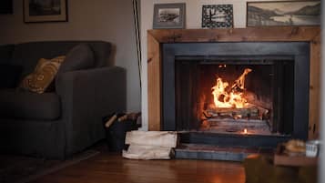 En stue med pejs, sofa og et tæppe.