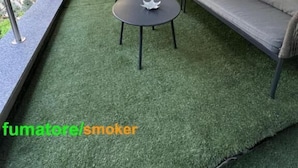 An outdoor seating area with a green artificial turf floor, a sofa, and two round tables. - hotel bolzano  (Milan)