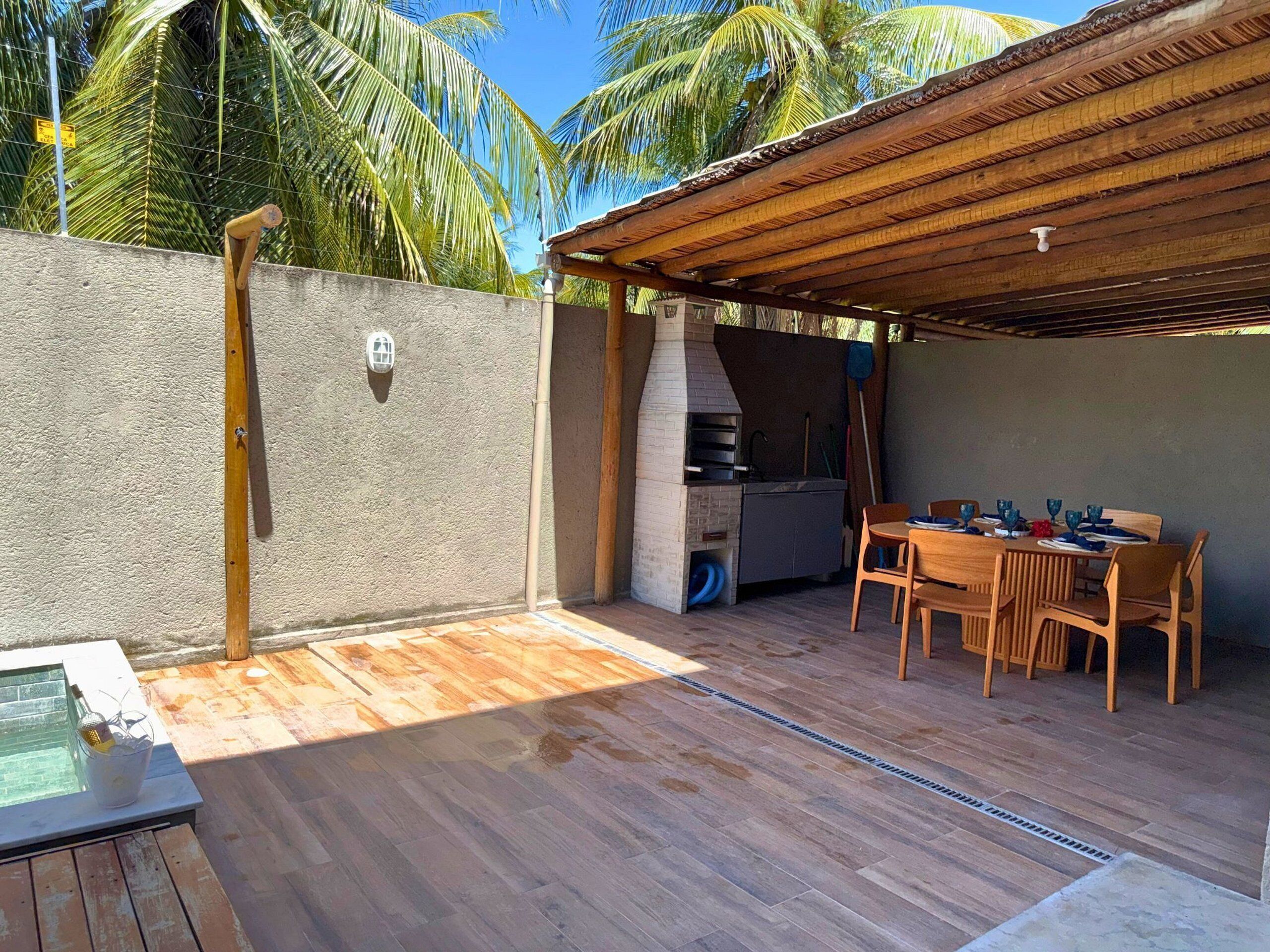An outdoor patio with a wooden table and chairs, a barbecue grill, and a pool.