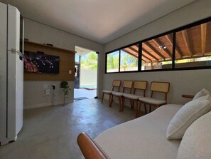 Una habitación con cama, televisor montado en la pared, zona de estar con sillas y vista por la ventana.